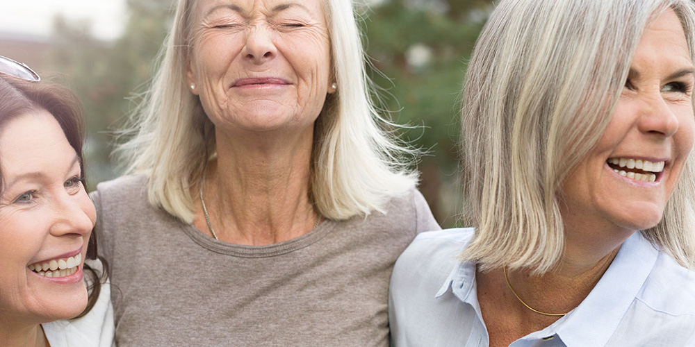 Three women laughing outdoors