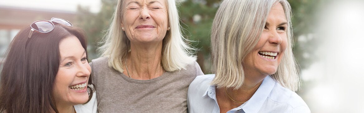 Three women laughing outdoors